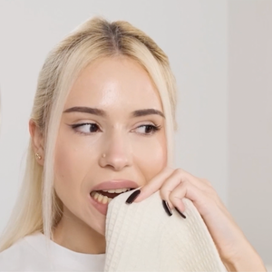 Mujer secándose los dientes con una toalla antes de aplicar las tiras blanqueadoras
