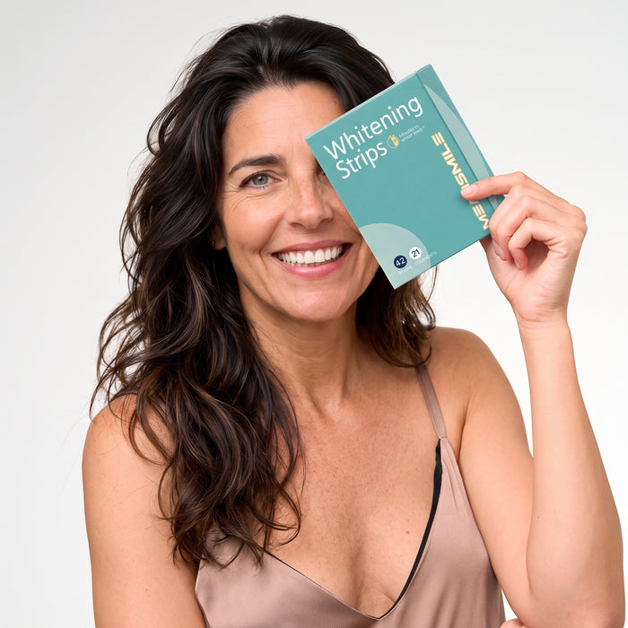 Mujer sonriendo mientras sostiene la caja de tiras blanqueadoras modosmile junto a la cara