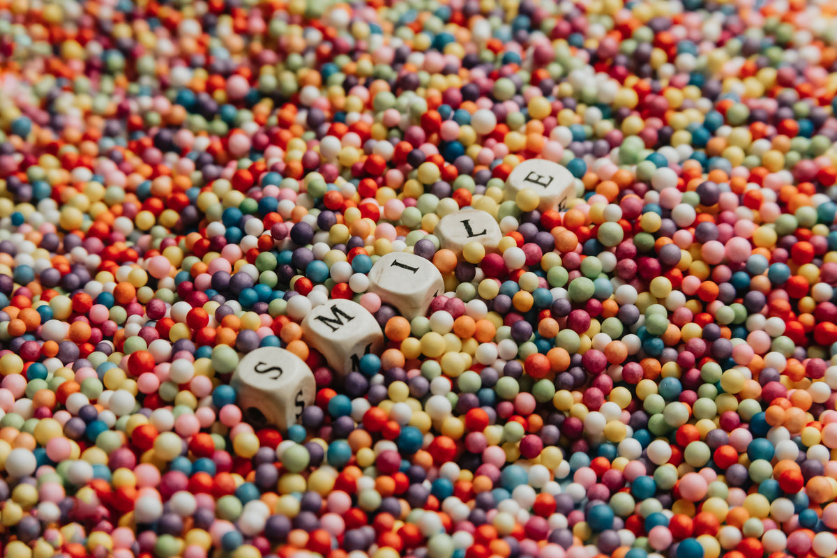 Dados de letras formando la palabra SMILE sobre bolitas de colores