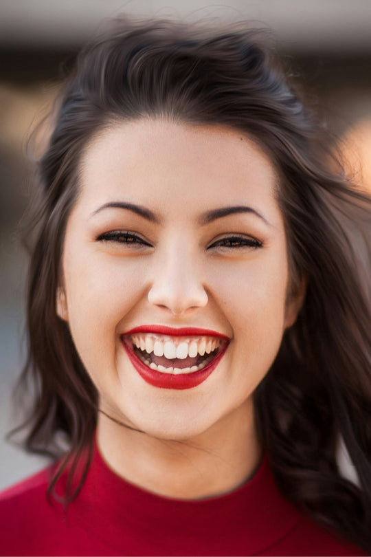 Mujer morena riendo con jersey rojo y labios rojos