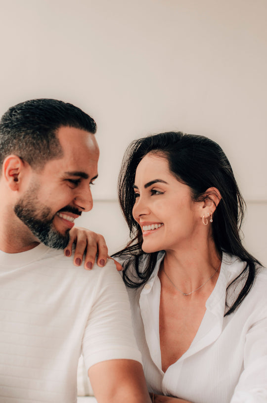 Pareja abrazada sonriendo sobre fondo claro